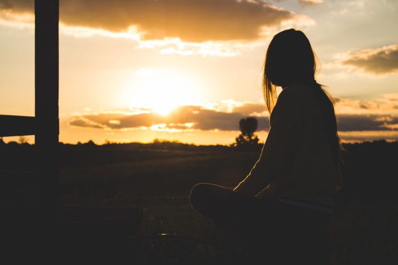 Silhouette di una donna che medita al tramonto